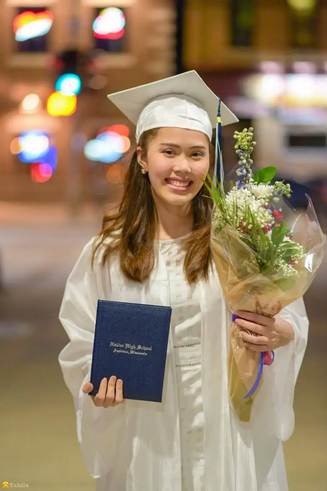 Graduate posing with flowers and diploma